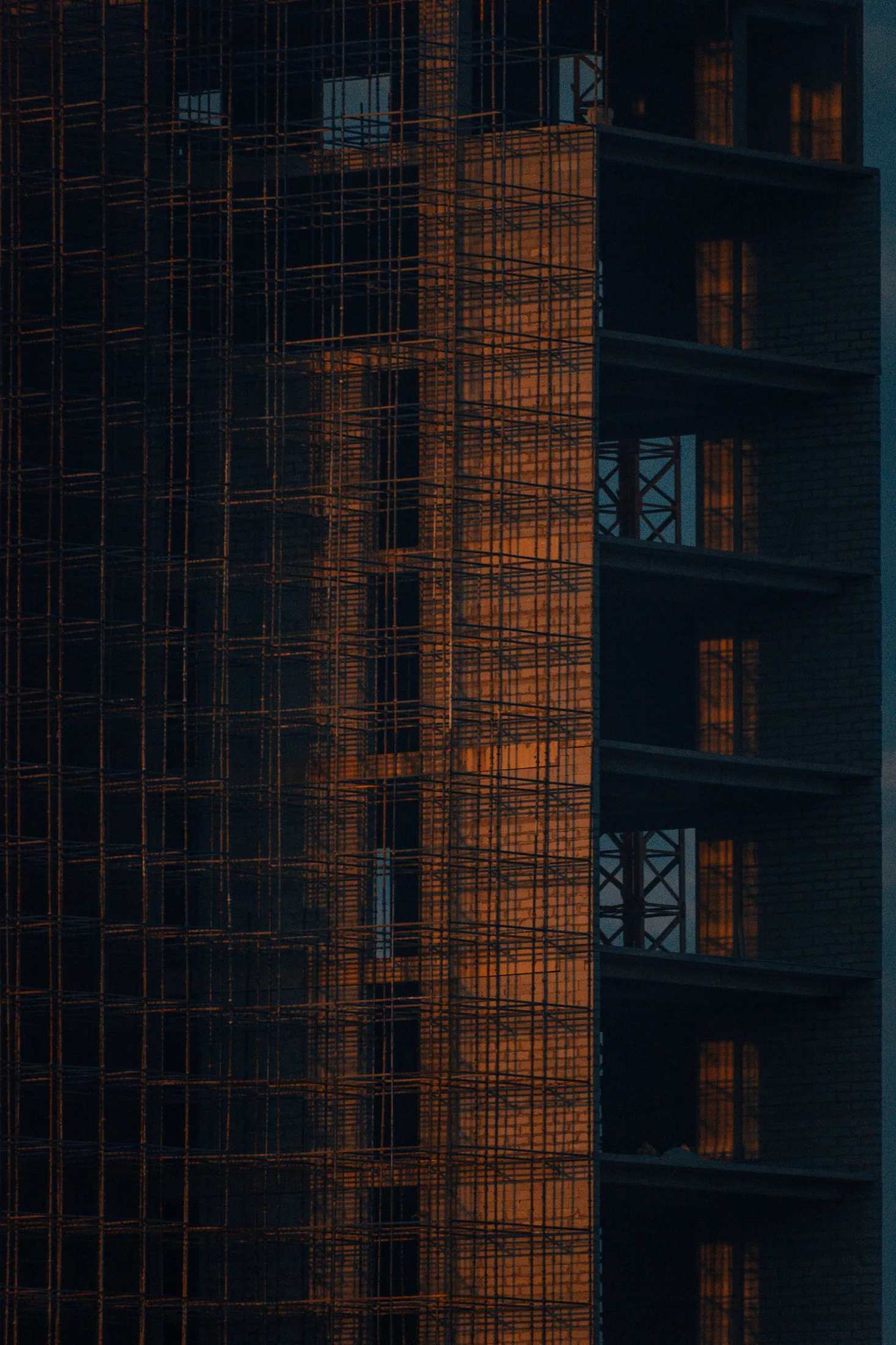 夕景の建築現場を包む仮設フレーム